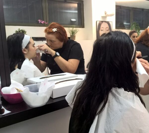 Students practising make-up on models in a training class