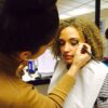 Student applying make-up to a model during training