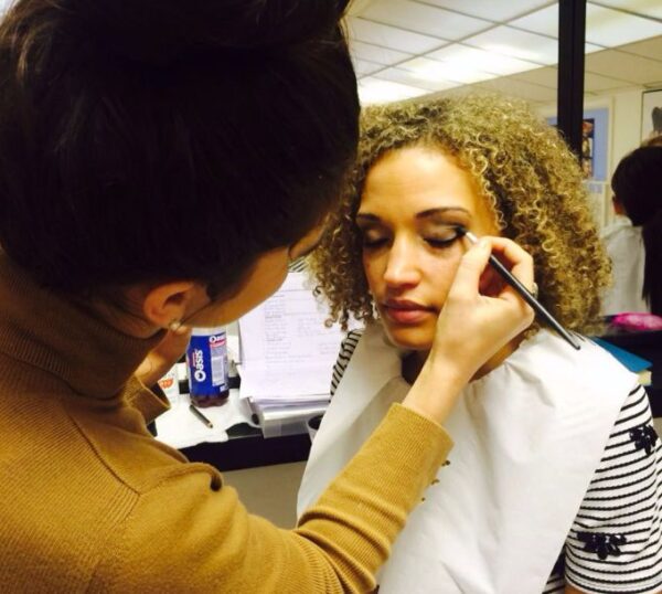 Student applying make-up to a model during training