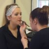 Student applying lip liner to a model
