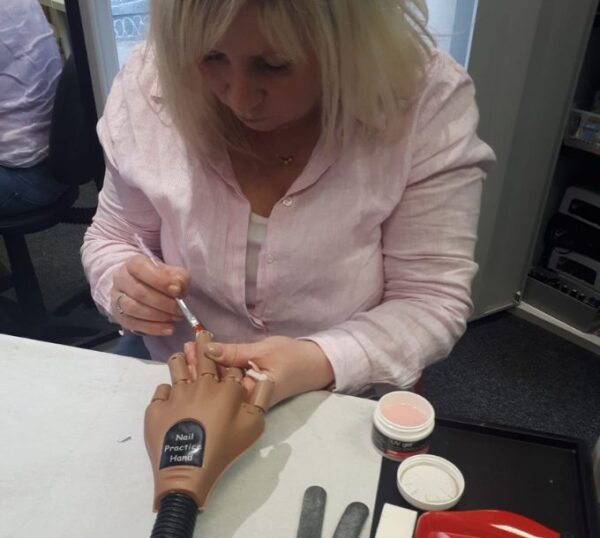 Student applying UV gel nail extensions