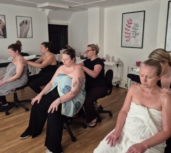 Students practising massage on each other in a training room