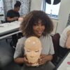 Smiling lash student with a practice mannequin head