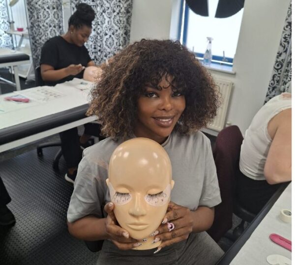 Smiling lash student with a practice mannequin head