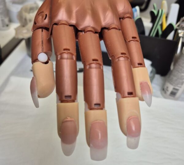 Acrylic nail extensions on a practice hand