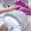Gel nails being cured under a UV lamp