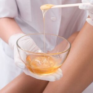 Waxing therapist with a spatula of warm wax