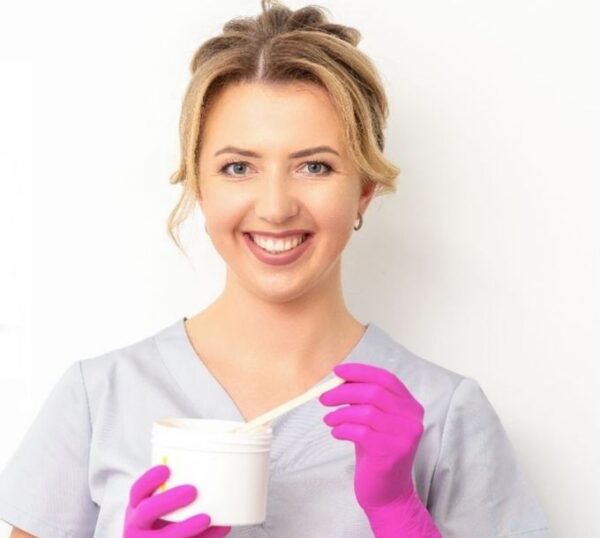 Smiling waxing therapist holding a wax spatula