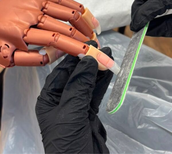 Nail extension being filed on a practice hand