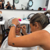 Student applying eye make-up to a model