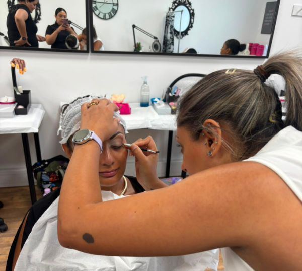 Student applying eye make-up to a model