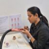 Student applying acrylic nail extensions to a practice hand