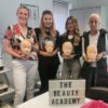 Smiling lash students holding practice mannequin heads