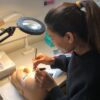 Student practising lash extensions under a magnifying lamp