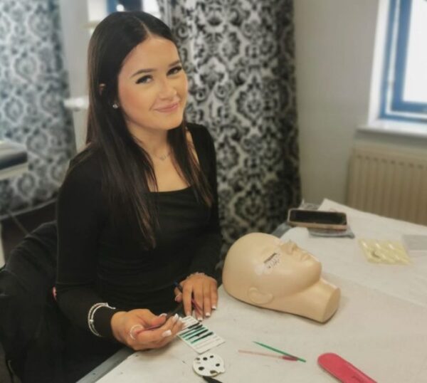 Smiling lash student with a practice mannequin head