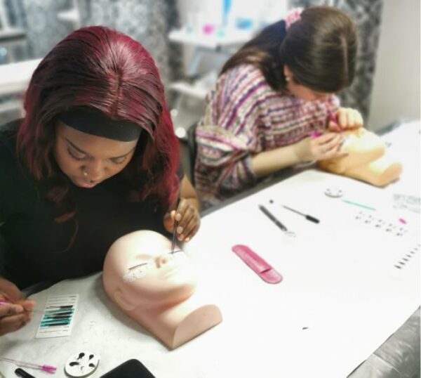 Students practising lash extensions on mannequin heads
