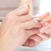 Nail technician pushing back cuticles during a manicure