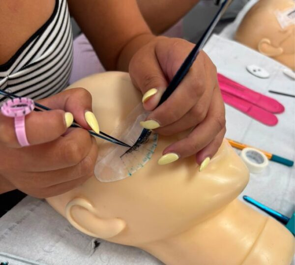 Hybrid lash extensions being applied to a practice mannequin