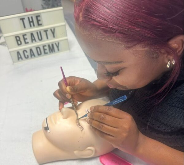 Student applying lash extensions to a practice mannequin