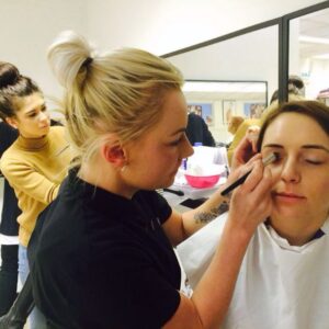 Students practising make-up application in a training class