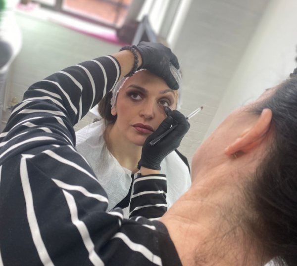 Student applying eye make-up to a model