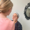 Student applying make-up to a model