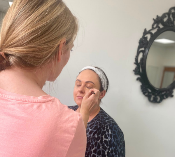 Student applying make-up to a model