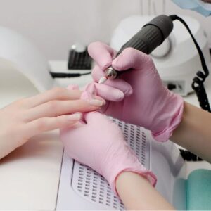 Nail technician using an electric e-file on a client's nails