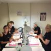 Smiling nail students at their training desks