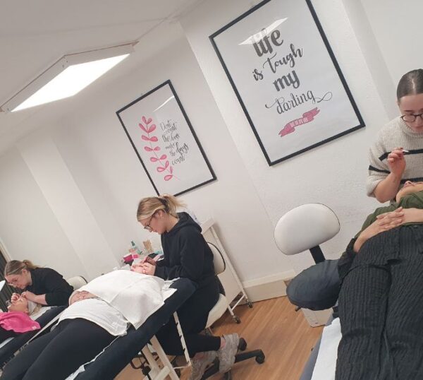 Students practising brow treatments in a training room
