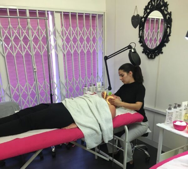 Student giving a facial in a training room