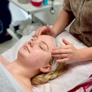 Student giving a facial massage in a training room