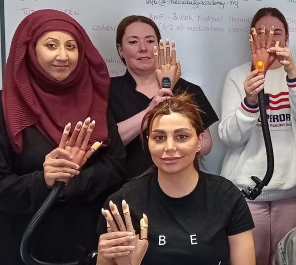 Smiling nail students showing their practice hands