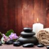 Massage stones and a candle on a wooden surface