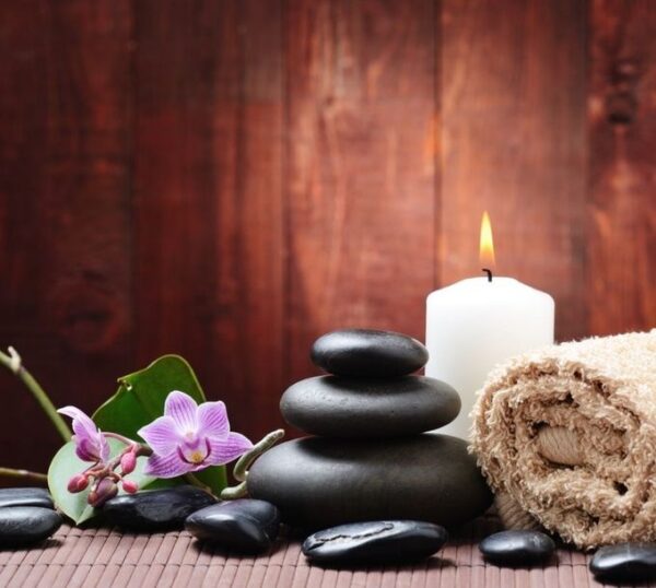 Massage stones and a candle on a wooden surface
