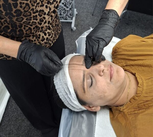 Student tinting a model's brows