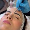Brows being tinted with a brush