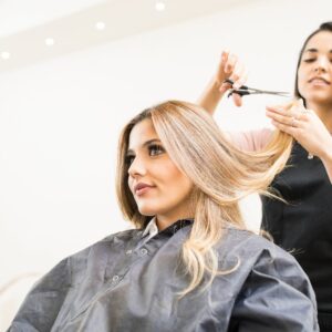 Hair technician cutting and blending a client's hair extensions