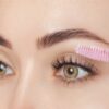 Mascara wand brushing through long lashes