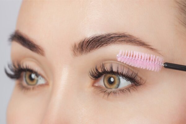 Mascara wand brushing through long lashes